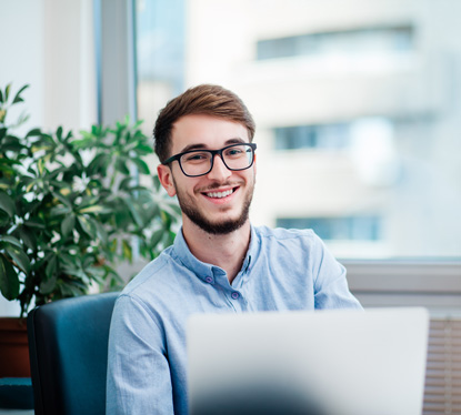 Jeune homme, content, devant son ordinateur portable