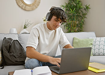 Jeune homme travaillant sur son ordinateur et écoutant de la musique avec un casque Jeune homme travaillant sur son ordinateur et écoutant de la musique avec un casque